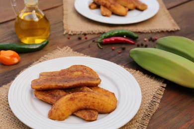 Photo of Delicious fried bananas, fresh fruits and different peppers on wooden table