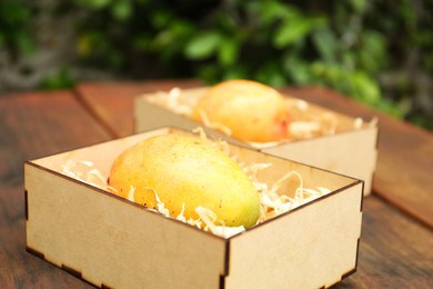 Delicious ripe juicy mangos on wooden table, closeup