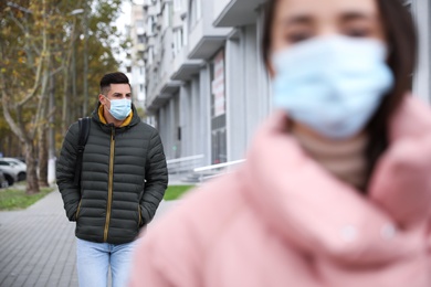 Photo of Man in medical face mask walking outdoors. Personal protection during COVID-19 pandemic