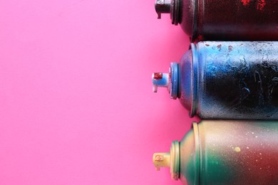 Photo of Many spray paint cans on pink background. Space for text
