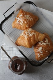 Delicious croissants with almond flakes and chocolate paste on light grey table, flat lay