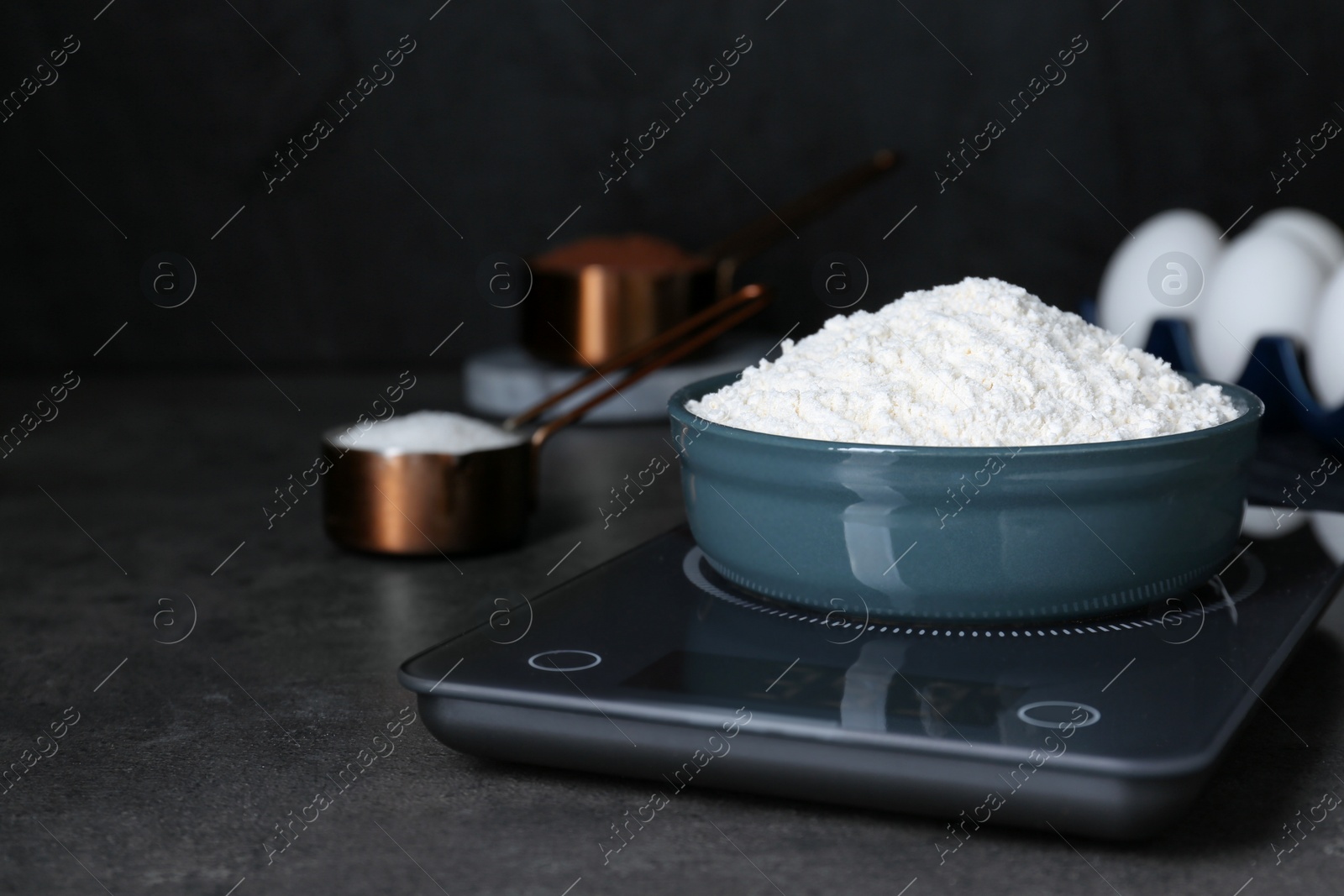 Photo of Electronic scales with flour on black table, space for text