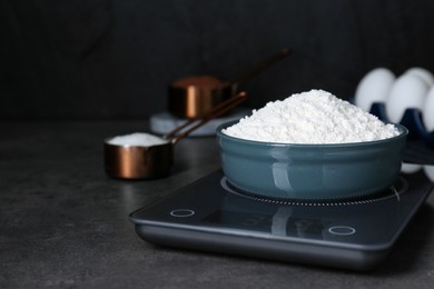 Electronic scales with flour on black table, space for text