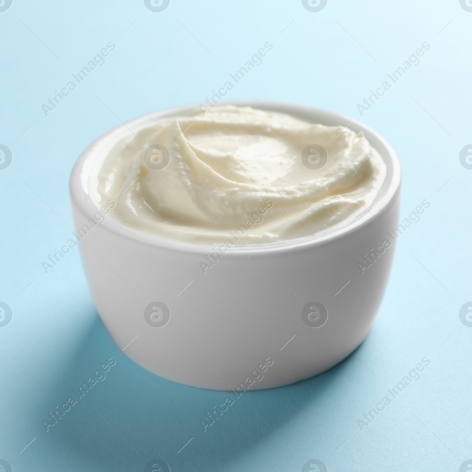 Photo of Bowl of tasty cream cheese on color background