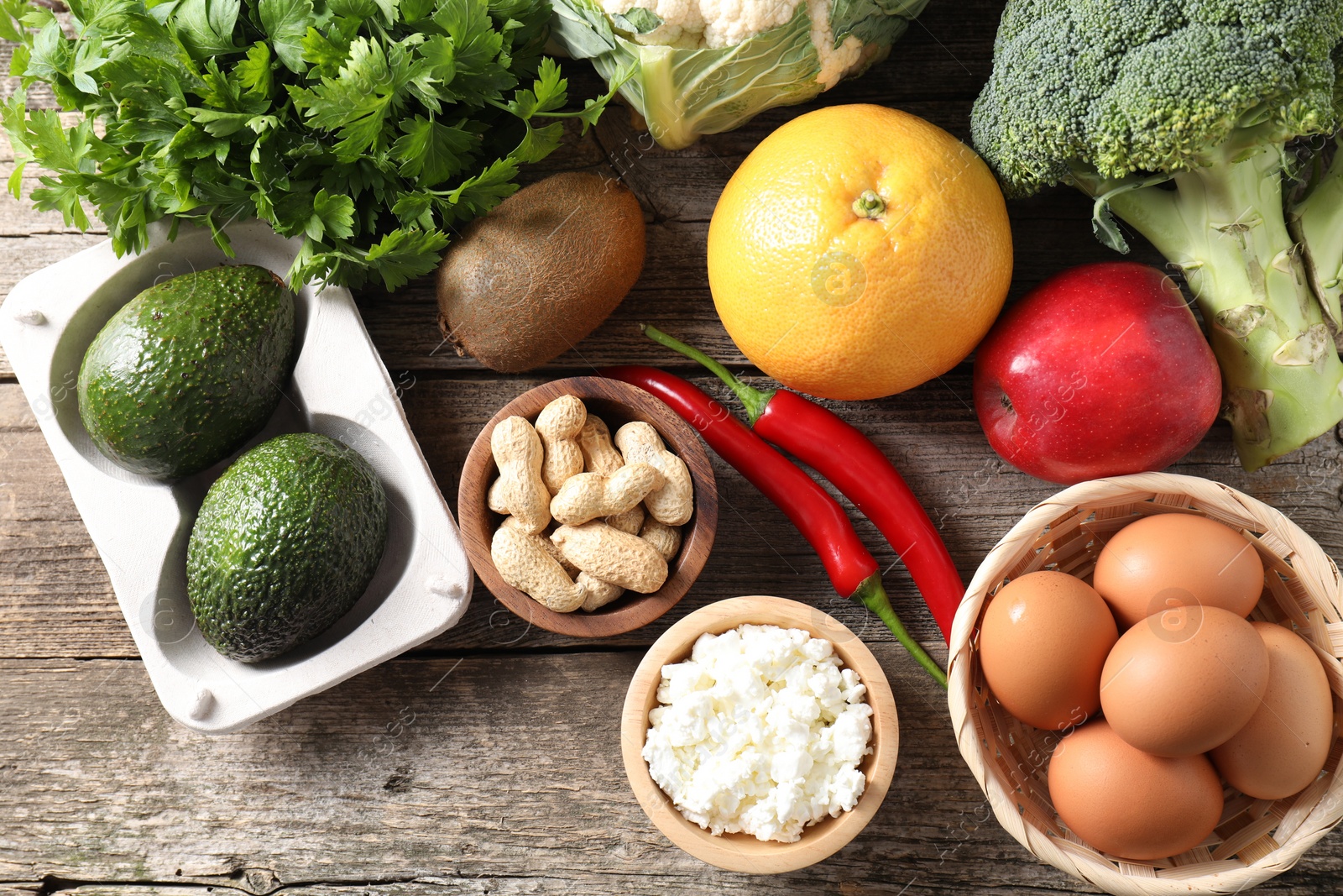 Photo of Healthy meal. Different vegetables and raw eggs on wooden table, flat lay