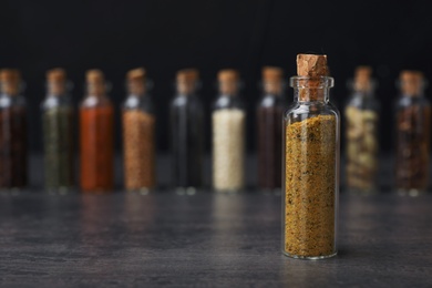 Photo of Glass bottle with spice on table against blurred background