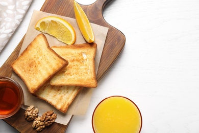 Tasty toasts and freshly made orange juice on white wooden table, flat lay. Space for text