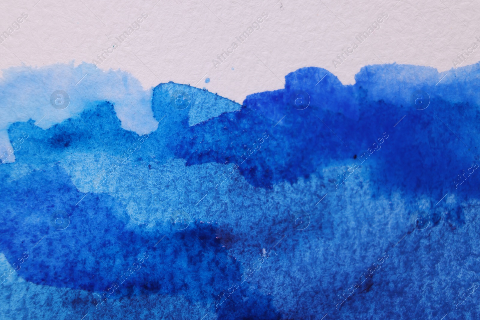 Photo of Abstract blue watercolor painting on white paper, top view