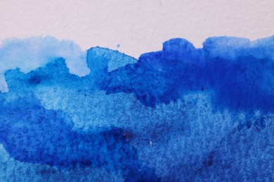 Abstract blue watercolor painting on white paper, top view