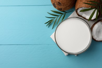 Bowl of delicious vegan milk, palm leaf and coconuts on light blue wooden table, flat lay. Space for text