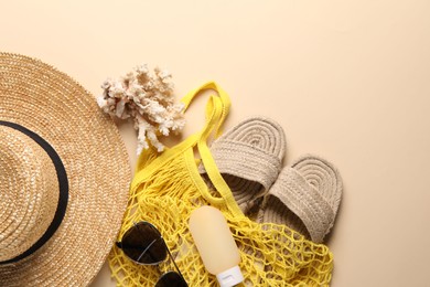 Photo of String bag and different beach accessories on beige background, top view. Space for text