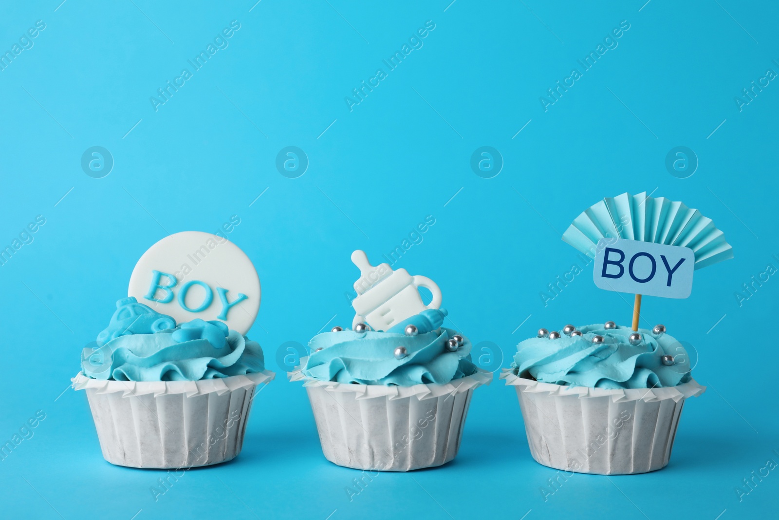 Photo of Baby shower cupcakes with toppers on light blue background