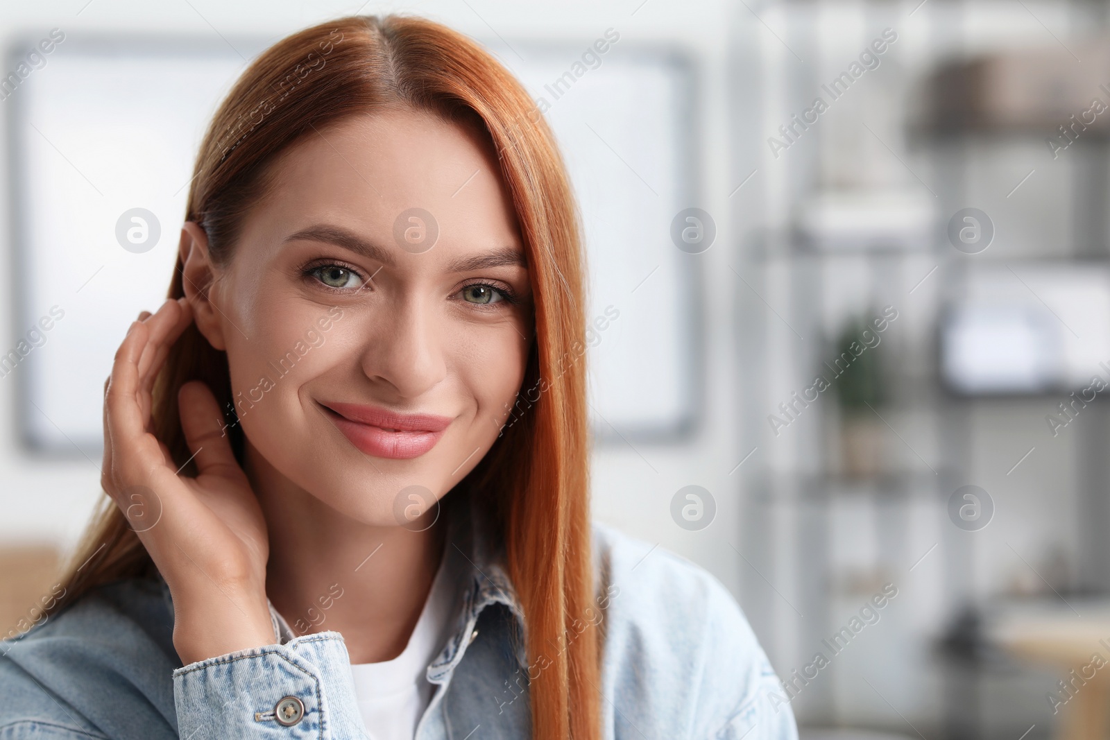 Photo of Portrait of beautiful young woman with red hair indoors. Attractive happy lady looking into camera. Space for text