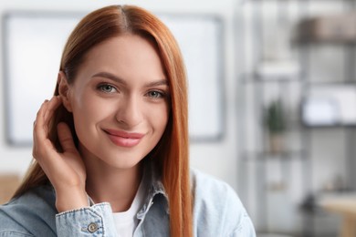 Portrait of beautiful young woman with red hair indoors. Attractive happy lady looking into camera. Space for text