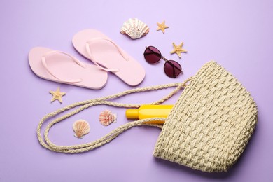 Stylish bag with beach accessories on violet background, flat lay