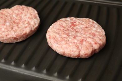 Photo of Fresh raw hamburger patties on grill pan, closeup