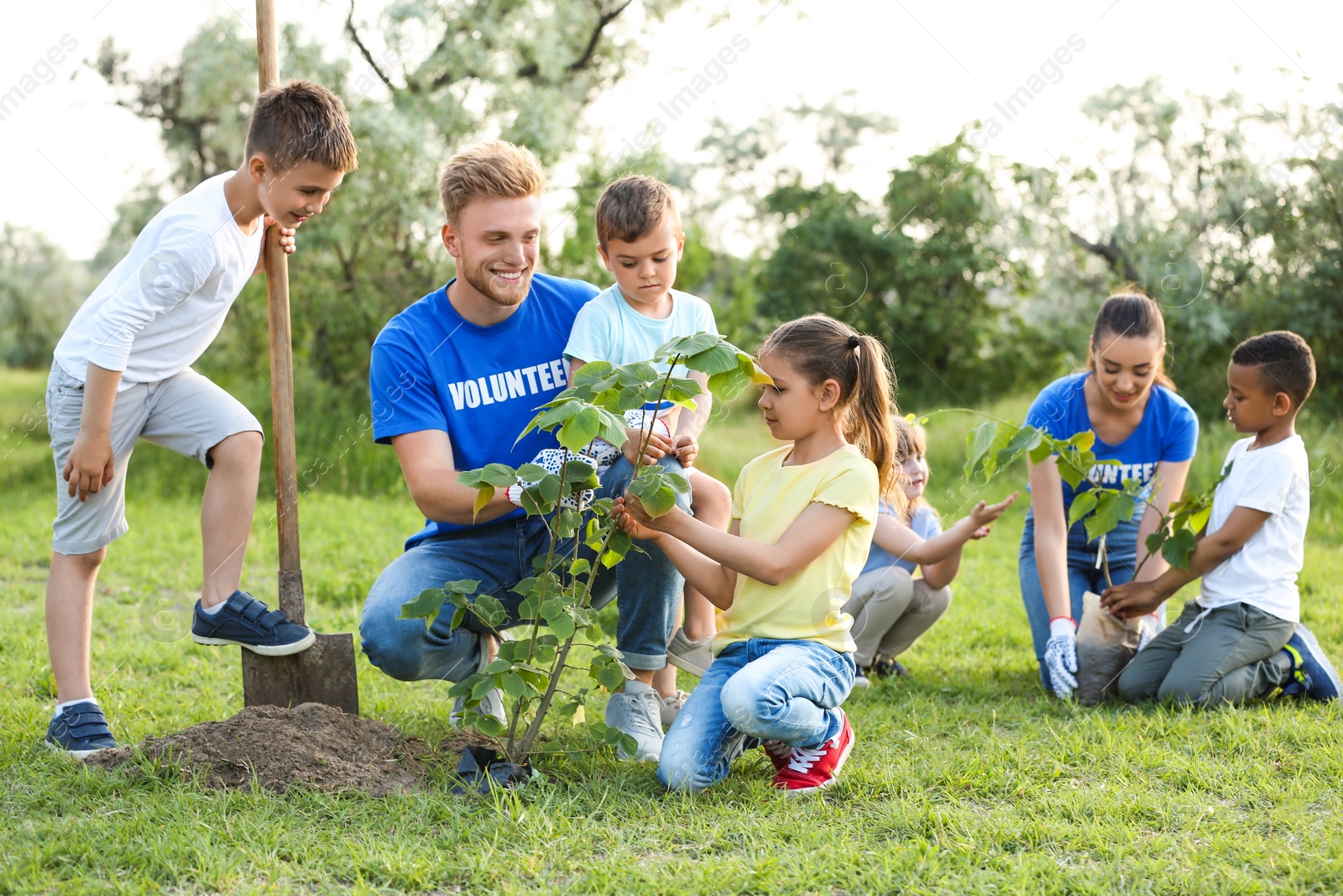 Photo of Kids planting trees with volunteers in park