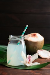 Glass jar of coconut water and beautiful flower on wooden table