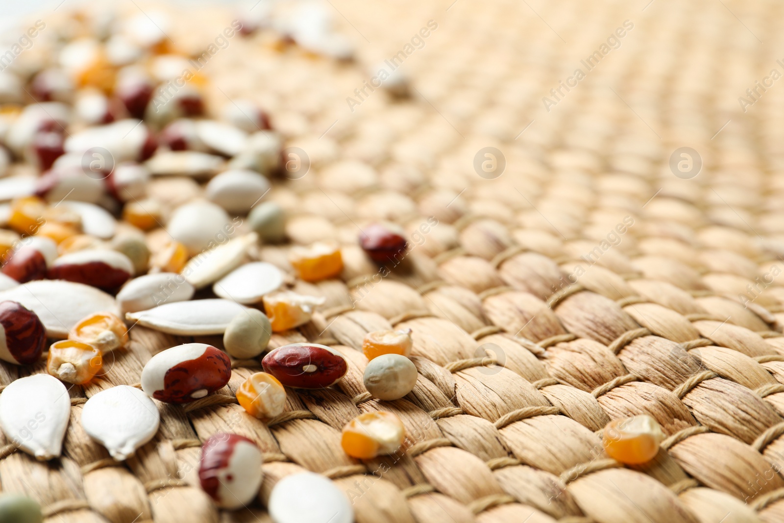 Photo of Mixed vegetable seeds on wicker background, closeup