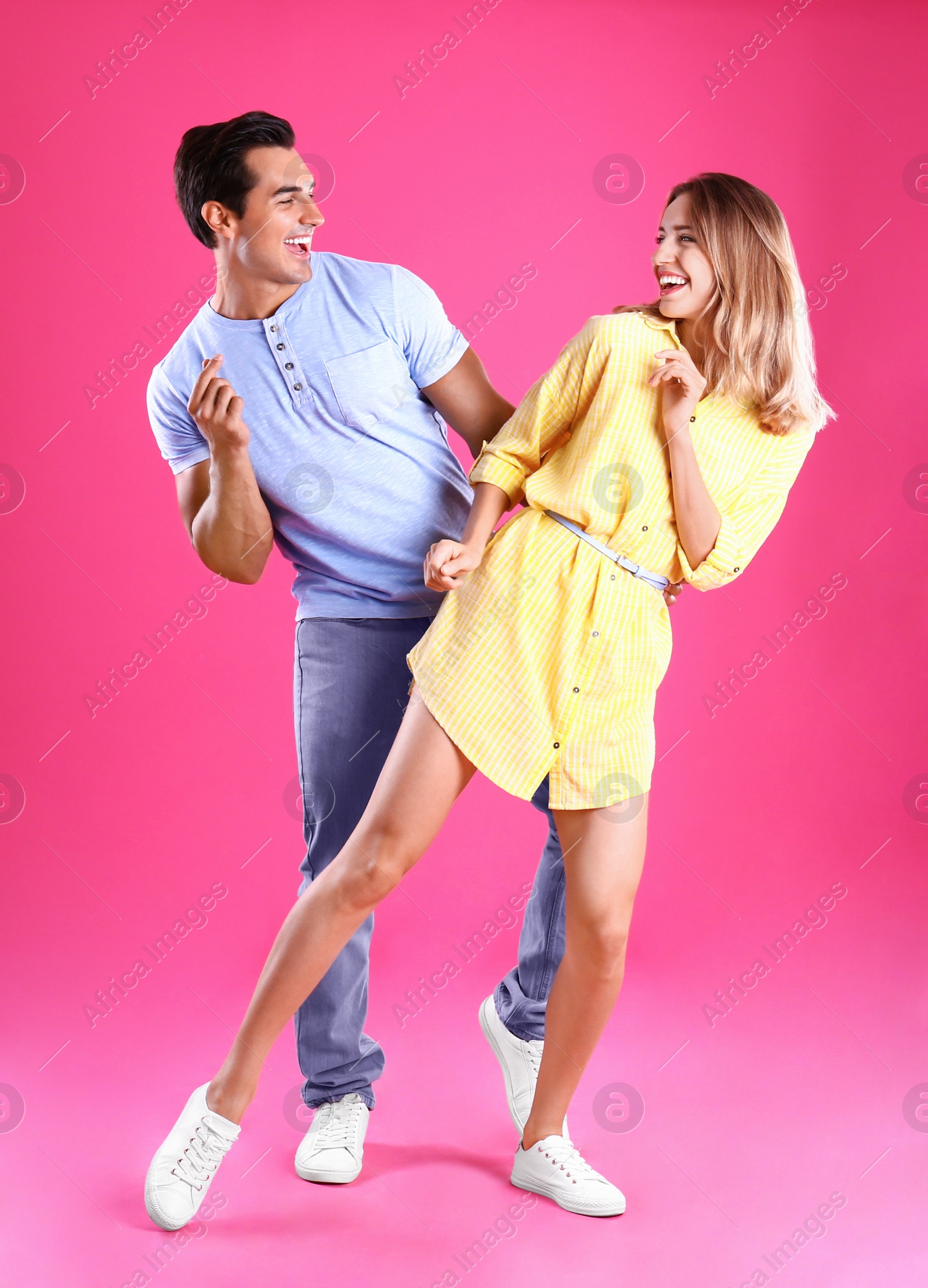 Photo of Beautiful young couple dancing on pink background