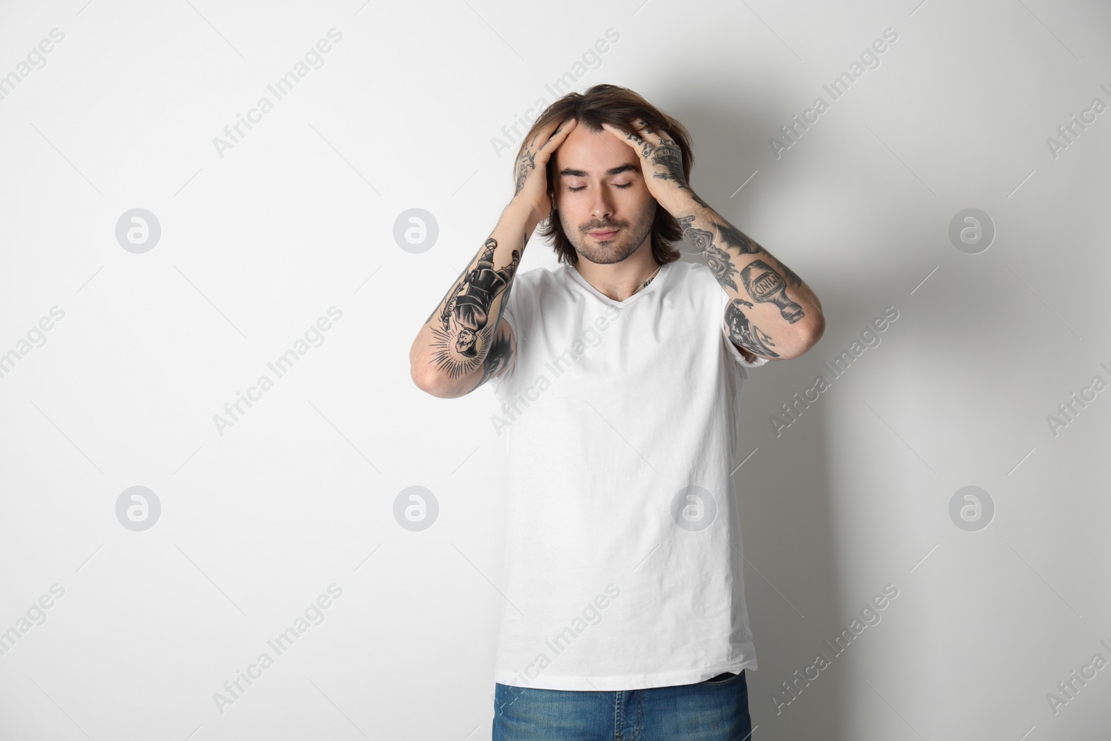 Photo of Young man with tattoos on arms against white background