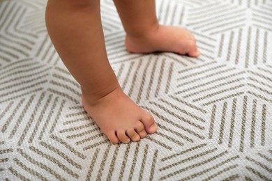 Photo of Cute baby learning to walk on carpet, closeup