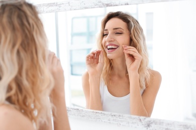 Young woman flossing her teeth in bathroom