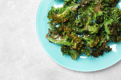 Tasty baked kale chips on light grey table, top view