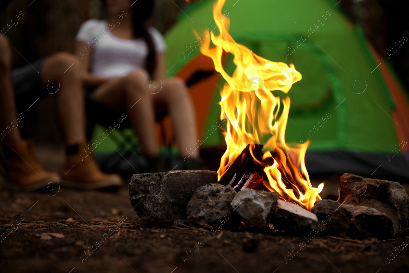 Photo of Beautiful bonfire with burning firewood near camping tent in forest