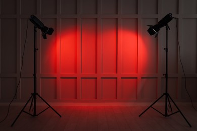 Photo of Bright red spotlights near wall indoors, space for text