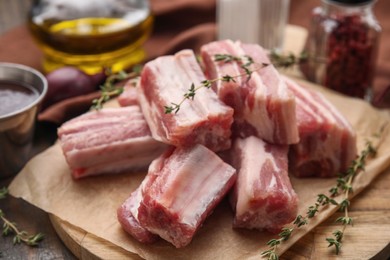 Photo of Cut raw pork ribs with thyme on table, closeup