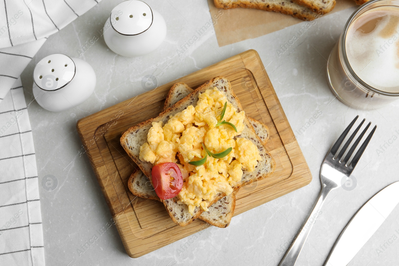 Photo of Tasty scrambled egg sandwich served on light grey marble table, flat lay