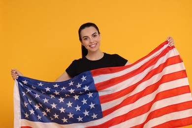 4th of July - Independence Day of USA. Happy woman with American flag on yellow background