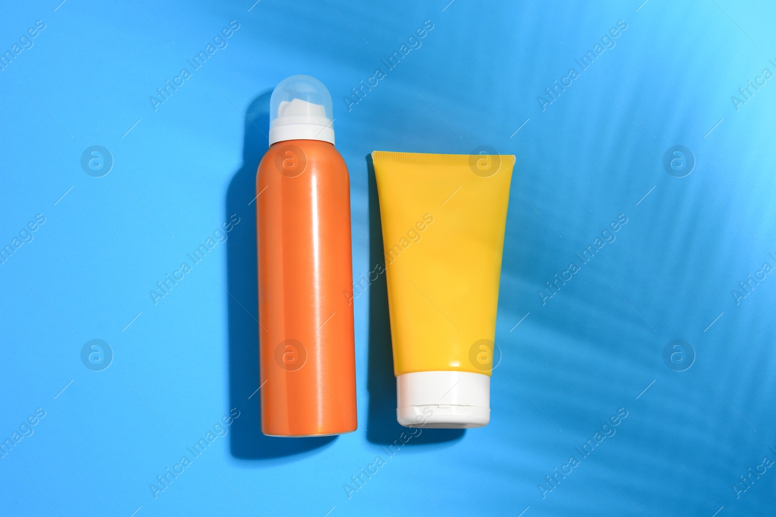 Photo of Sunscreens on light blue background, flat lay. Sun protection care