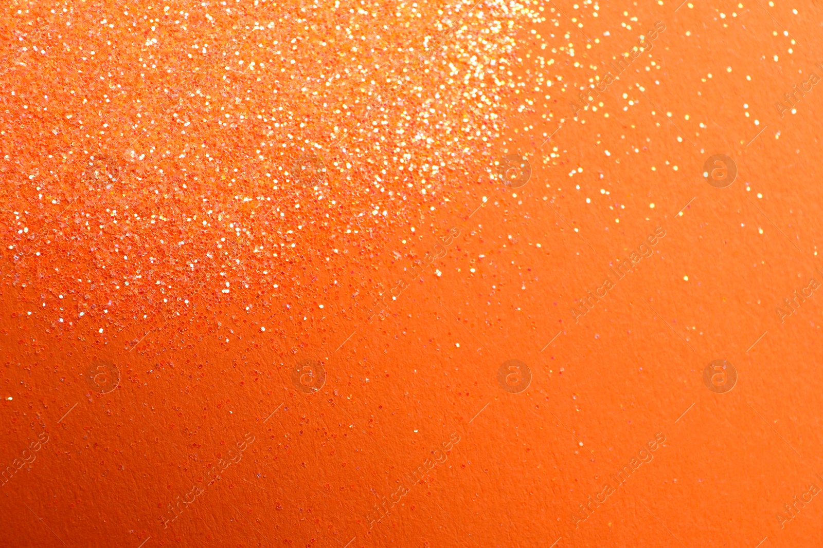 Photo of Shiny bright glitter on orange background, flat lay. Space for text