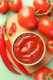 Bowl of tasty ketchup and ingredients on green table, flat lay