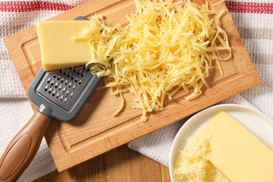 Grated, whole pieces of cheese and grater on wooden table, top view