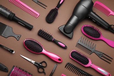 Photo of Flat lay composition of professional hairdresser tools on brown background