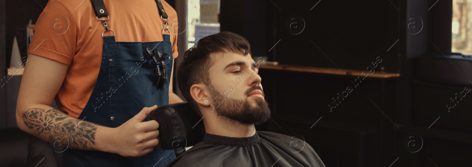 Image of Professional hairdresser working with bearded client in barbershop, space for text. Banner design