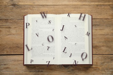 Image of Open book with letters flying out of it on wooden background, top view