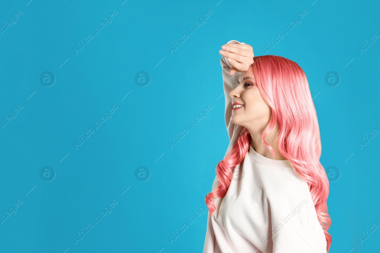 Image of Portrait of young woman with dyed long curly hair on blue background, space for text