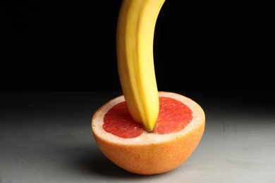 Fresh grapefruit and banana on table against black background. Sex concept