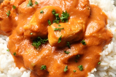 Photo of Delicious butter chicken with rice as background, closeup
