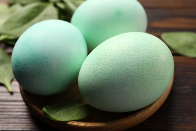 Photo of Naturally painted Easter eggs on wooden table, closeup. Spinach used for coloring