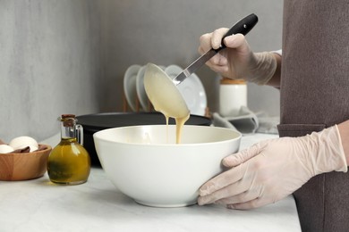 Photo of Woman cooking delicious crepe at white marble table in kitchen, closeup