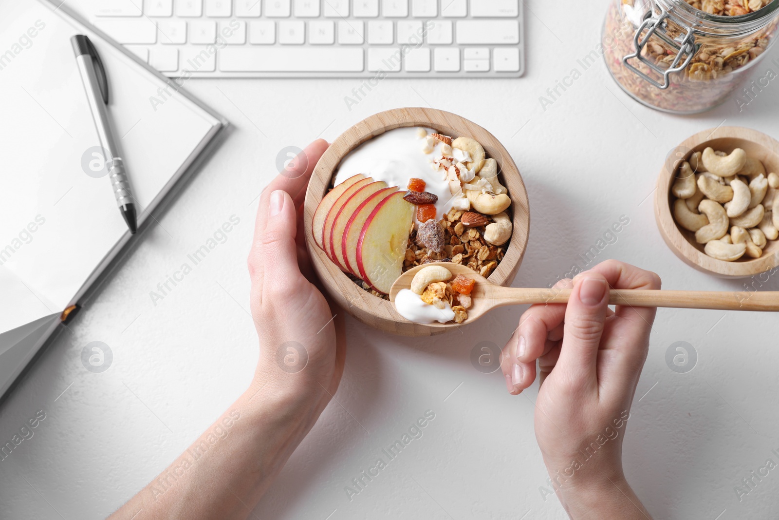 Photo of Woman eating tasty granola at workplace, top view