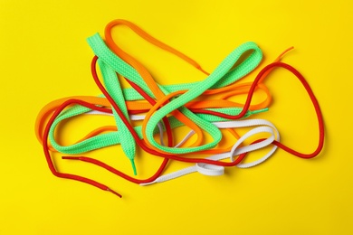 Photo of Colorful shoelaces on yellow background, flat lay