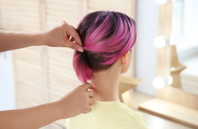 Photo of Professional hairdresser working with young woman in beauty salon. Trendy hair color