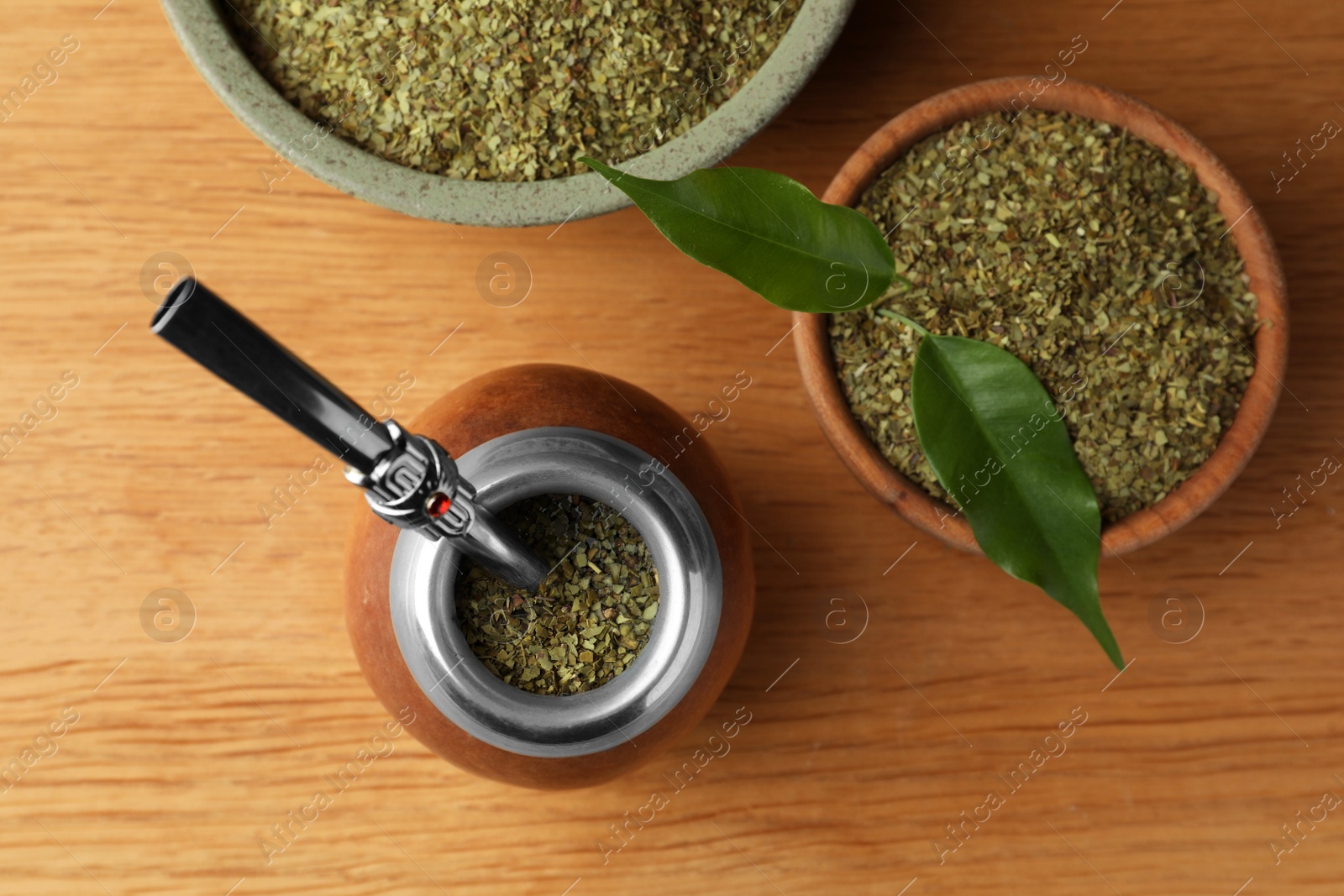 Photo of Calabash with mate tea and bombilla on wooden table, flat lay