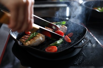 Photo of Professional chef cooking meat on stove in restaurant kitchen, closeup